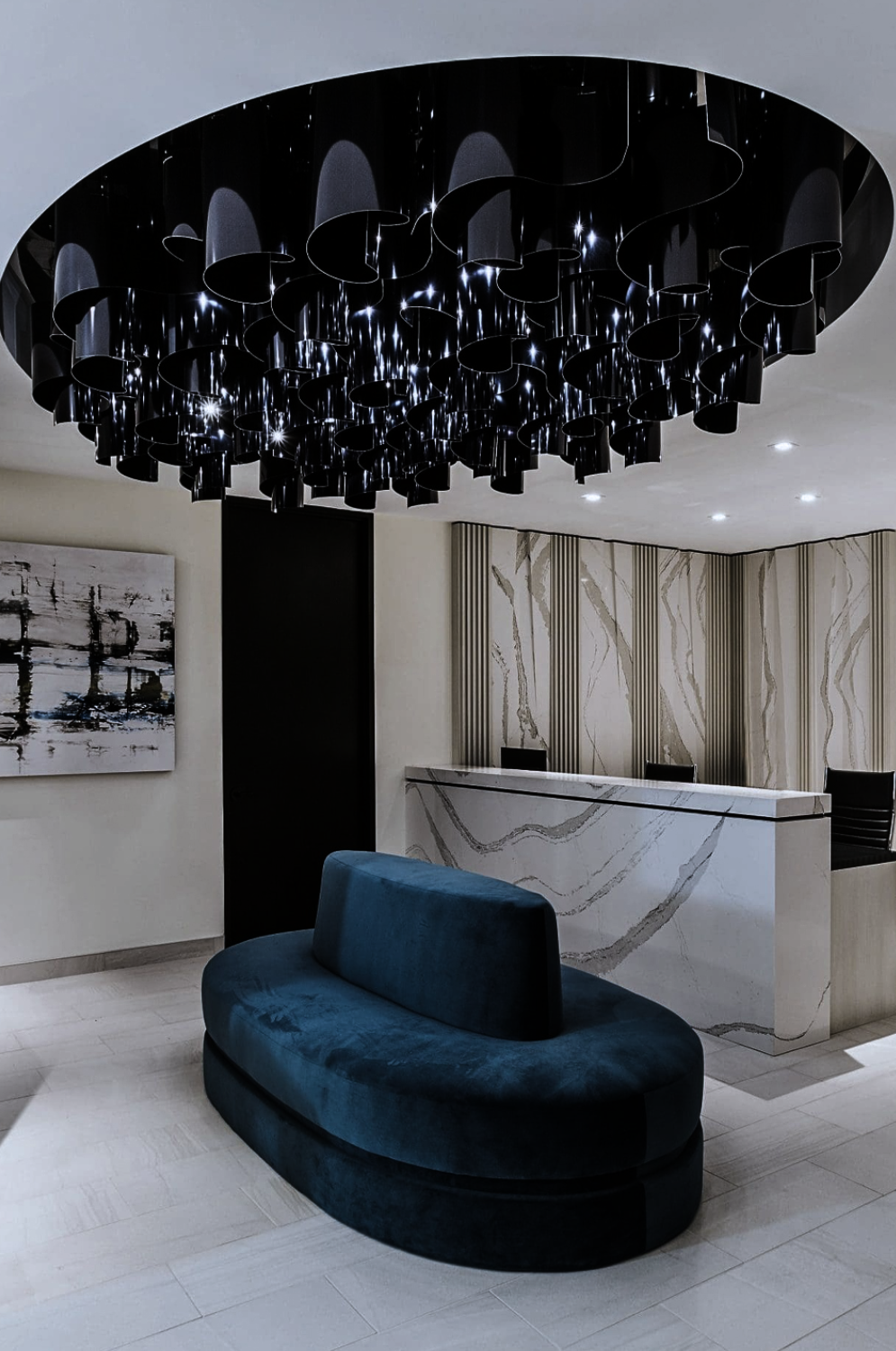 BBR lobby designed by Nina Magon Studio features a sculptural black chandelier above a marble reception desk and curved velvet seating.