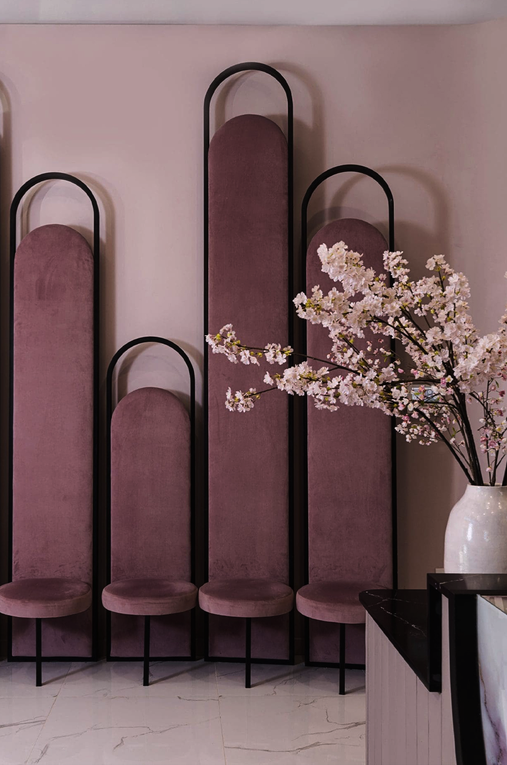 Gloss Nail Bar designed by Nina Magon Studio featuring blush curved panels, black metal frames, and cherry blossoms.