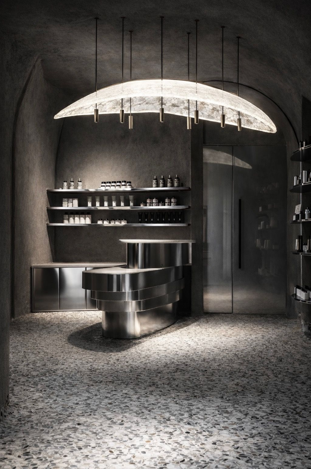 Minimalist spa retail room at Lico Spa & Wellness by Nina Magon Studio with sculptural lighting and curved displays.