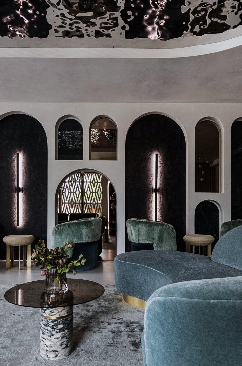 Nina Magon Lounge designed by Nina Magon Studio with velvet seating, arched niches, brass accents, and marble table.