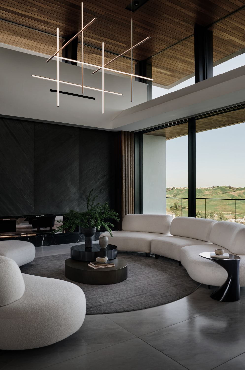 Los Angeles Hills living room by Nina Magon Studio with curved sectional, sculptural tables, and floor-to-ceiling hillside views.