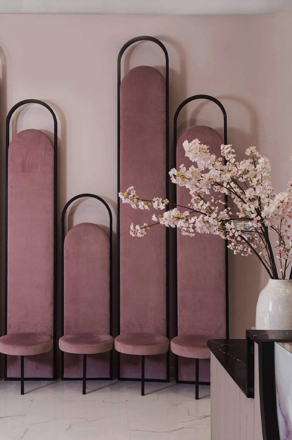 Gloss Nail Bar designed by Nina Magon Studio featuring blush curved panels, black metal frames, and cherry blossoms.